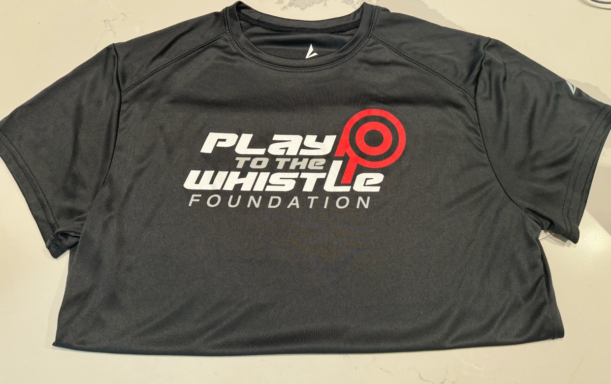 A black shirt that says play to the whistle foundation.