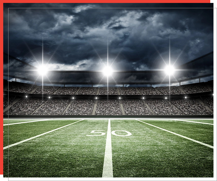 A football field with the lights on at night.